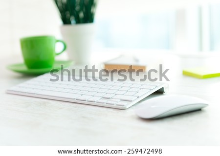 Office table with notepad, computer, flower and coffee cup