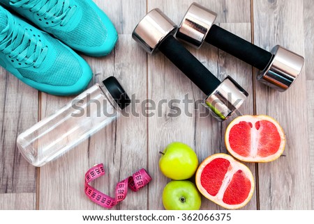 Fitness equipment. Healthy food. Sneakers, water,apple  on wooden background