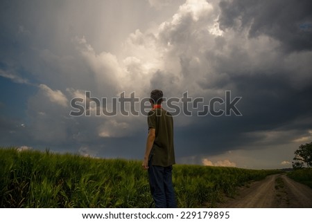 Young man in front of a storm cloud in the field