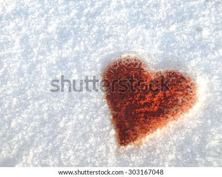 Sparkling strong love illustrated by a heart made of chili-powder on a snow background