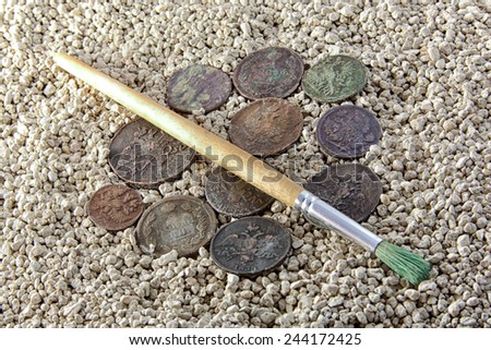 old coins in the sand and brush clearing