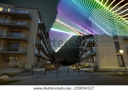 light beam passing through a residential / apartment building. It is evening / night and the colored light beams are clearly visible - buildings are Scandinavian / Copenhagen