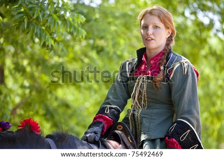 WAXAHACHIE,TX - APRIL 16 : The Joust - New Riders of the Golden Age - Red-headed woman trainer in medieval costume riding a horse at Scarborough Renaissance Festival - April 16, 2011 in Waxahachie, Texas.