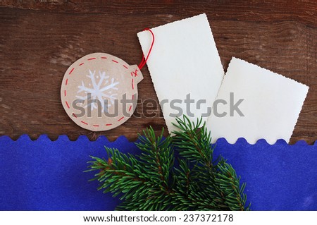 Paper New Year\'s toy and two empty cards on an old wooden background with a fir-tree branch on a blue paper background/ Christmas decorative paper jewelry