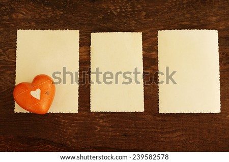 Three empty ancient photographs and heart on an old brown wooden background/ Three empty photographs and heart on an old wooden background