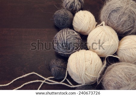 gray and white spheres of a yarn on a wooden table/woolen balls for knitting on a wooden background