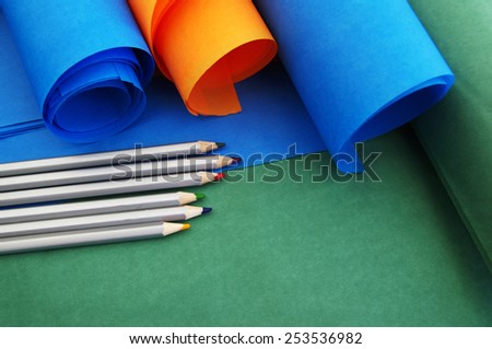 Bright rolls of color paper with colored pencils close up