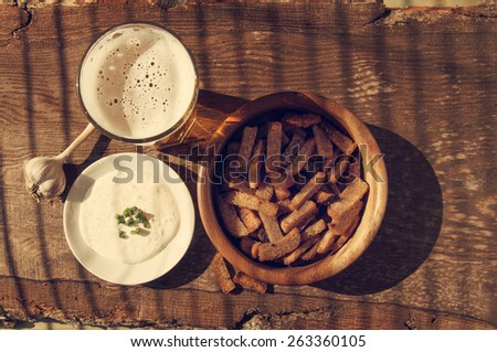 Beer in a glass, croutons and garlick sauce on a structural wooden table. Beer and snack to beer.