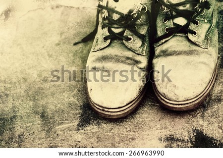Old dirty boots with the untied laces on grunge a background. Old footwear.