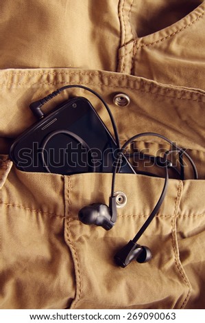 Mobile phone and earphones in a pocket