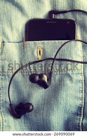 Mobile phone and earphones in a shirt jeans pocket