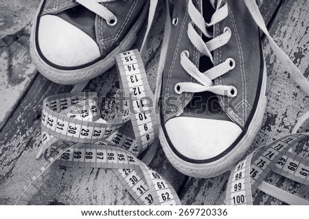 Sneakers and meter on old wooden surface. Sport shoes. Black and white