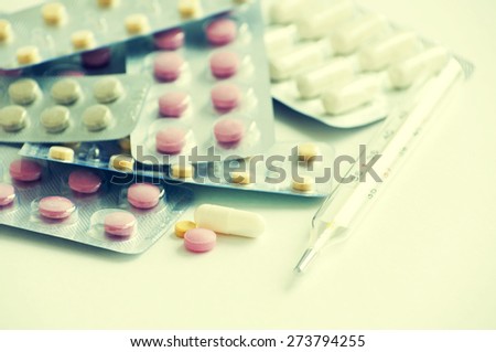 Color pills in plates and thermometer on a light background. Medicine.