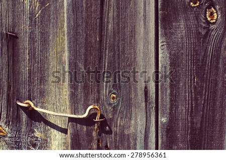 The door hook closes an old wooden door. Textural wooden background