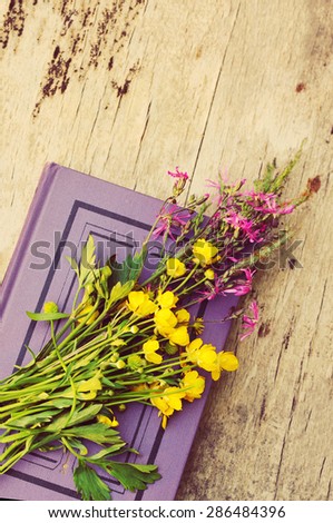 Spring bouquet of flowers and the book on a wooden surface