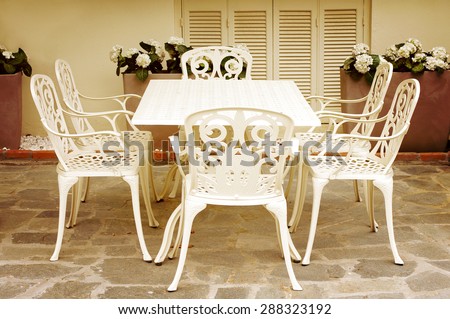White figured chairs and table in cafe. Six white chairs round a table