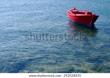Red Mediterranean fishing boat in the sea in a summer sunny day. Lonely red boat