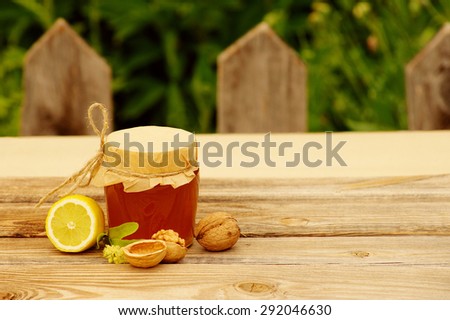 Honey, lemon, walnuts and flowers of a linden on a table against a wooden fence