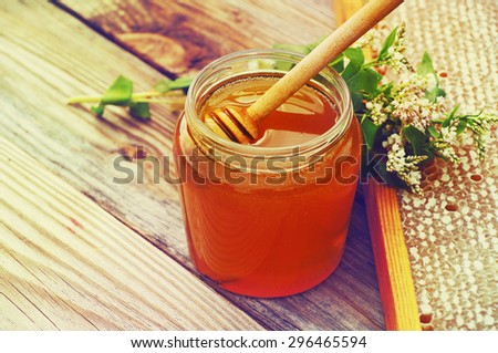 Honey in a glass jar, buckwheat flowers and bee honeycombs in a summer sunny day. Honey with flowers and honeycombs