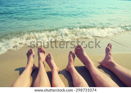 Female, children\'s and male feet on a beach against the sea in a summer sunny day. Family holiday