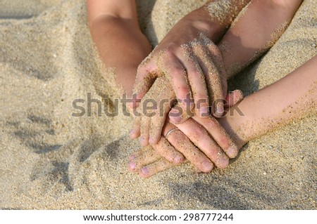 Mother and the son intertwined hands on a beach. Hands of mother and the child represent a unity oath