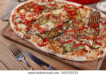 Pizza with chicken, zucchini, eggplant and mushrooms on wooden rustic table
