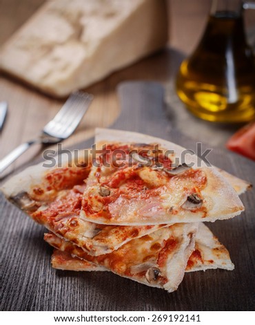 Sliced tasty pizza with ham and mushrooms on wooden table