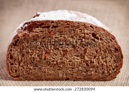 Fresh whole grain bread with a nuts, sunflower seeds, spices and vegetables on rustic background