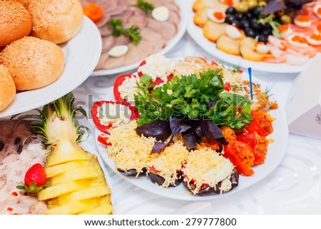 Buffet table served with tasty meals. Stuffed vegetables and cream cheese decorated with greens