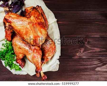 Roasted Turkey. Thanksgiving table served with turkey, decorated with greens and basil on dark wooden background. Homemade roasted chicken. Christmas holiday dinner. Top view