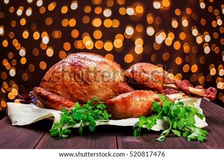 Roasted Turkey. Thanksgiving table served with turkey, decorated with greens and basil on dark wooden background. Homemade roasted chicken. Christmas holiday dinner