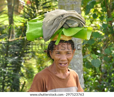 BALI, INDONESIA - JANUARY,09: a farmer woman carrying on top of her head a leaves of banana, on January,09, 2014 in Ubud,Bali, Indonesia.