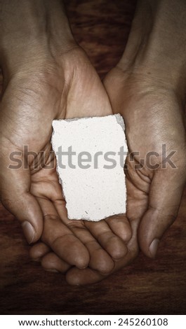Blank stone block in hands with dark background.