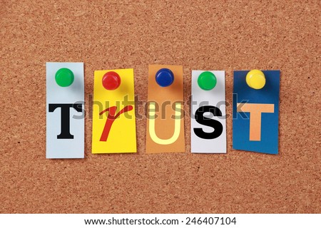 The word Trust in cut out magazine letters pinned to a cork board.