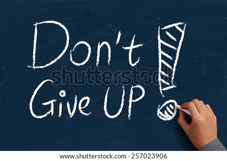 Do not give up on blue chalkboard with the hand of businessman.