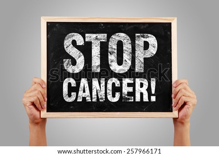 Stop Cancer blackboard is holden by hands with gray background.