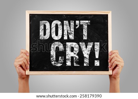 Do Not Cry blackboard is holden by hands with gray background.