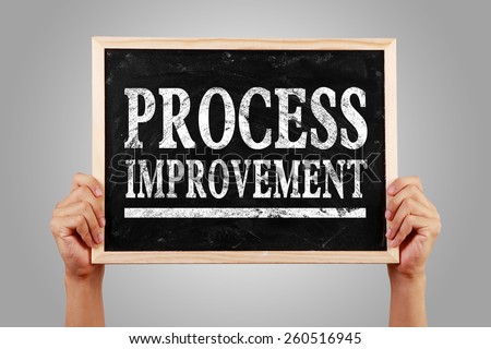 Hands are holding the blackboard of Process improvement against gray background.