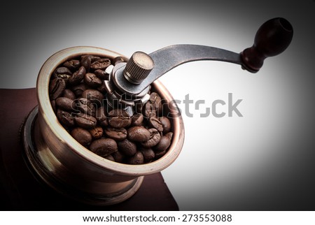 Close up fresh coffee bean in coffee bean grinder next to coffee bean.