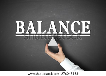 Balance concept with businessman hand holding against blackboard background.