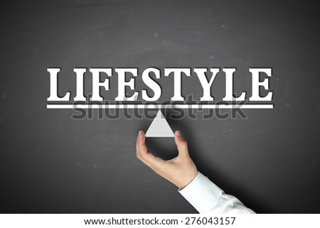 Lifestyle balance concept with businessman hand holding against blackboard background.