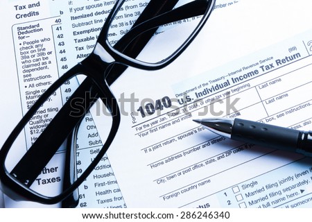 Tax form business financial concept with a pair of black glasses and a pen aside.