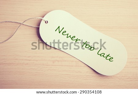 Never too late label is on the wooden desk background.