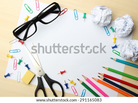 School supplies with white paper on the wood desk background.