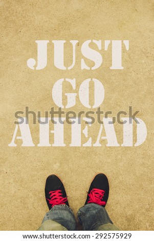 Just go ahead text is painted on the ground in front of the feet.