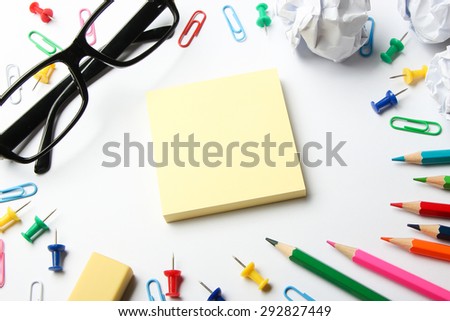 School supplies and blank sticky note block on the white paper background.