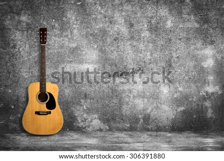 Acoustic guitar is against old style wall.