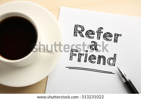 Text Refer a friend written on the white paper with pen and a cup of coffee aside.