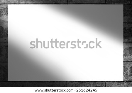 Blank white poster hanging on brick wall black and white background-light sunrays through the wall