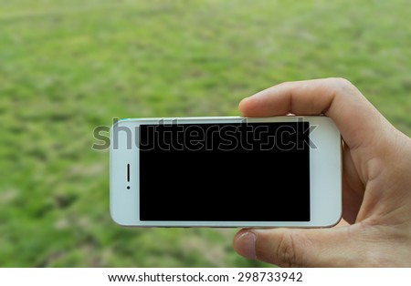 Hand holding smart phone with green blur background